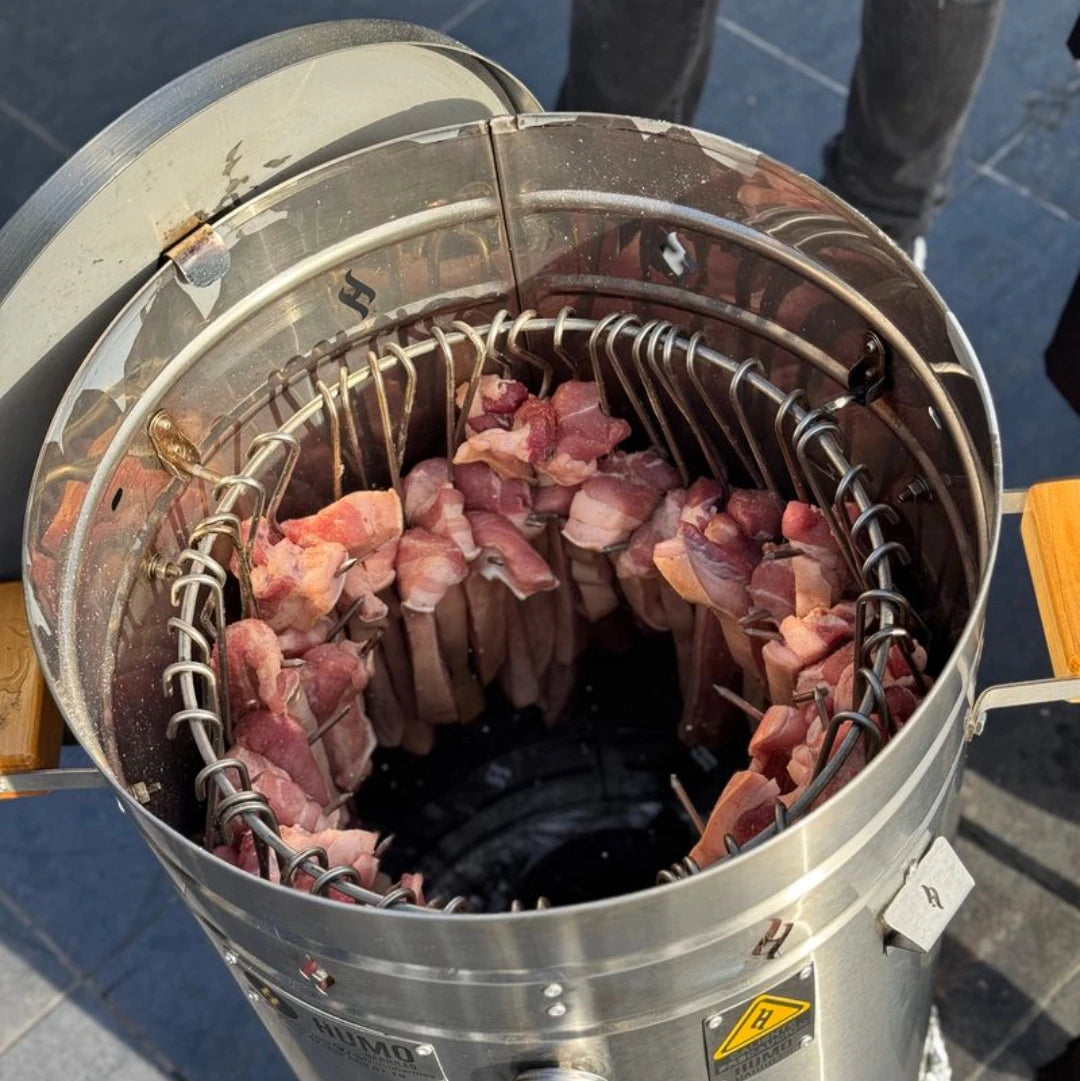 Carne colgada en los ganchos dentro del barril ahumador durante el proceso de ahumado
